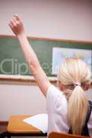 back view of a schoolgirl raising her hand