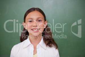 Cute schoolgirl standing in front of a blackboard