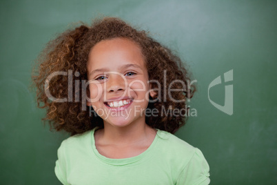 Schoolgirl posing in front of an empty chalkboard