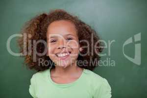 Schoolgirl posing in front of an empty chalkboard