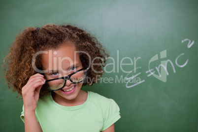 Smart schoolgirl looking above her glasses