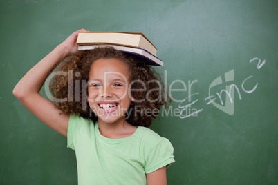 Cheerful schoolgirl holding her book on her head