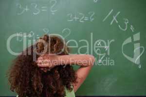 Schoolgirl thinking about mathematics while scratching the back