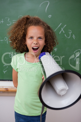 Portrait of a young schoolgirl screaming through a megaphone