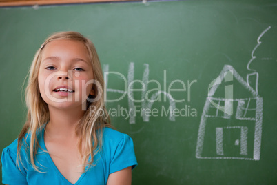 Blonde schoolgirl posing in front of a blackboard