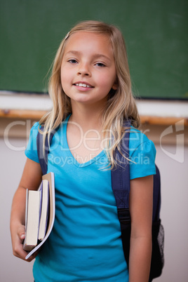 Portrait of a blonde schoolgirl holding her books