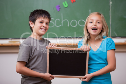 Happy pupils holding a school slate