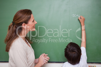 Happy schoolteacher helping a schoolboy doing an addition