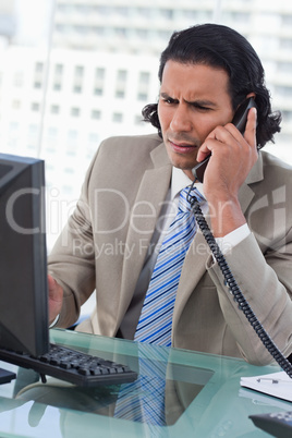 Portrait of a confused businessman working with a monitor while