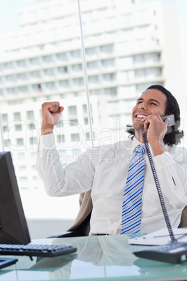 Portrait of a delighted businessman on the phone with the fist u