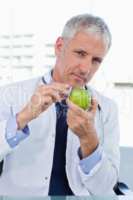 Portrait of a doctor putting his stethoscope on an apple