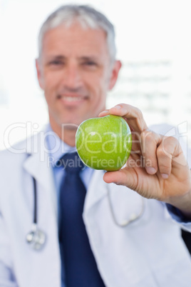 Portrait of a doctor showing an apple