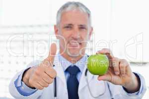 Doctor showing an apple with the thumb up