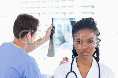 Male doctor looking at a of X-ray while his colleague is posing