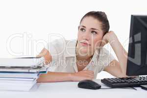 Dreaming businesswoman leaning on her desk