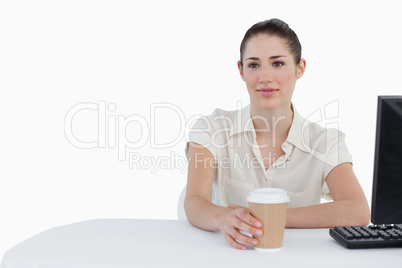 Businesswoman drinking a takeaway coffee while using a computer