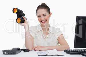 Smiling businesswoman holding binoculars
