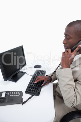Side view of a secretary answering the phone while using a compu