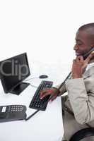 Side view of a male secretary answering the phone while using a