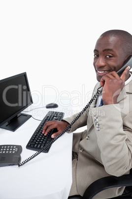 Side view of a male secretary answering the phone while using a