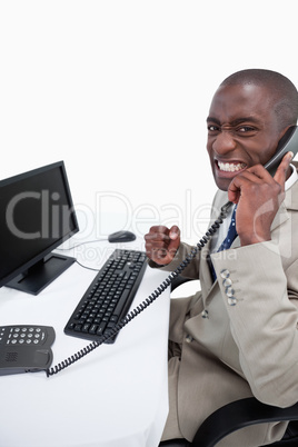 Side view of a businessman answering the phone while using a mon