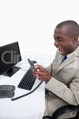 Portrait of an angry businessman answering the phone while using