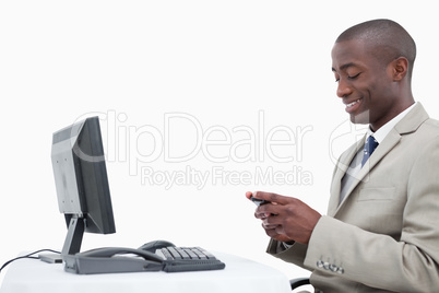 Side view of a smiling businessman sending a text message