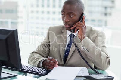 Entrepreneur making a phone call while looking at his computer