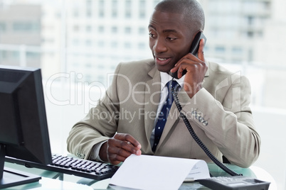 Smiling entrepreneur making a phone call while looking at his co