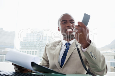 Angry businessman looking at his phone handset