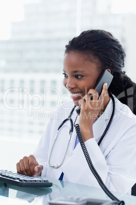 Portrait of a female doctor on the phone while using a computer