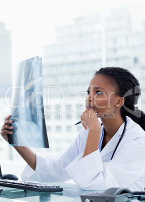 Portrait of a serious female doctor looking at a set of X-rays