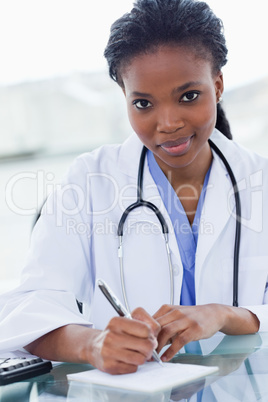 Portrait of a young female doctor writing a prescription