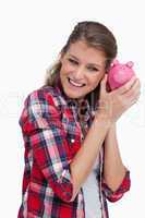 Portrait of a young woman shaking a piggy bank