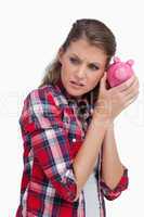 Portrait of a sad woman shaking a piggy bank