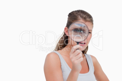 Young woman looking through a magnifying glass