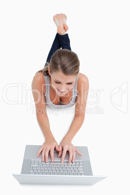 Portrait of a woman using a laptop while lying on the floor
