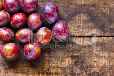 Fresh plums on old wooden table