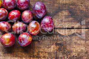 Fresh plums on old wooden table