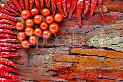 ripe cherry tomatoes and dried red chillies on rustic stripped bark
