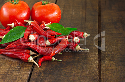 Dried red chillies and tomato on a rustic wooden table