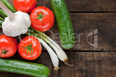 Tomatoes, cucumber, garlic and spring onions on old wooden table