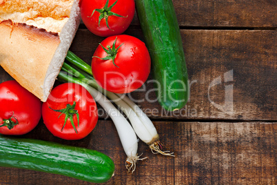 Tomatoes, cucumber, bread and spring onions on old wooden table
