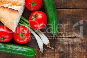 Tomatoes, cucumber, bread and spring onions on old wooden table