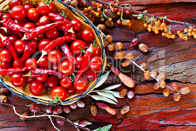 Basket of ripe cherry tomatoes and dried red chillies on rustic