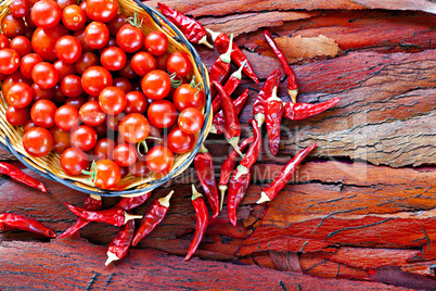 Basket of ripe cherry tomatoes and dried red chillies on rustic