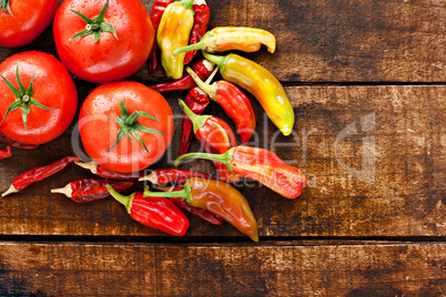 Assortment of chilli peppers and tomato on a rustic wooden table