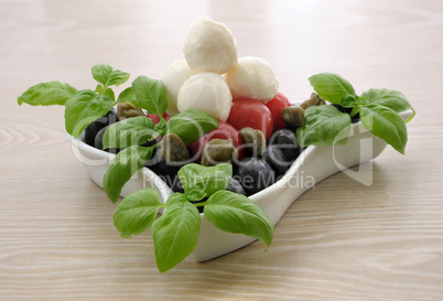 Appetizer of mozzarella, cherry tomatoes and olives and basil