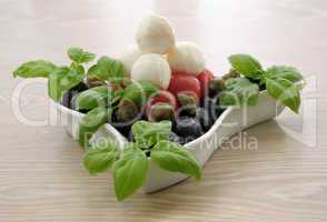 Appetizer of mozzarella, cherry tomatoes and olives and basil