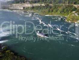 A boat in a river next to Niagara falls